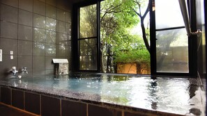A bathtub with a view of trees through a window. - Oyado Yumechidori (Saga)