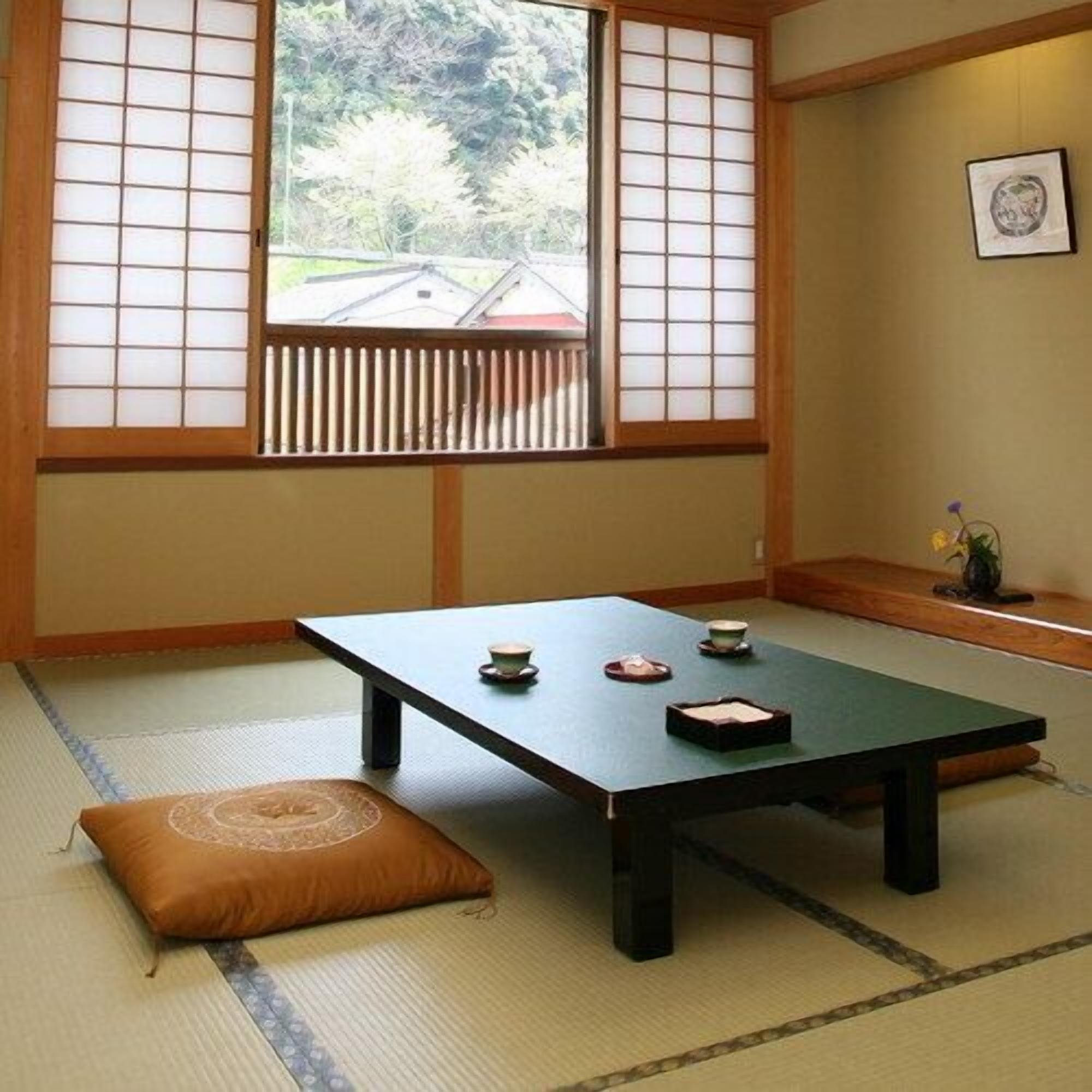 A traditional Japanese room with tatami flooring, a low table with tea utensils, and shoji screens.