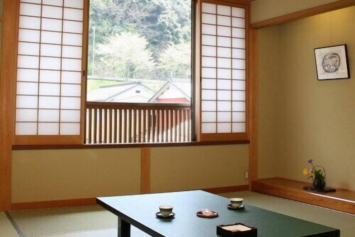 A traditional Japanese room with tatami flooring, a low table with tea utensils, and shoji screens.