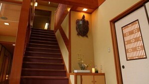 A wooden staircase leading to a room with a traditional Japanese sliding door and a decorative turtle sculpture.