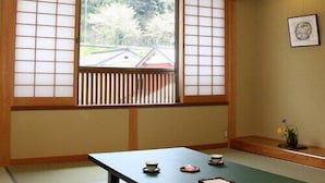 A traditional Japanese room with tatami flooring, a low table with tea utensils, and shoji screens.