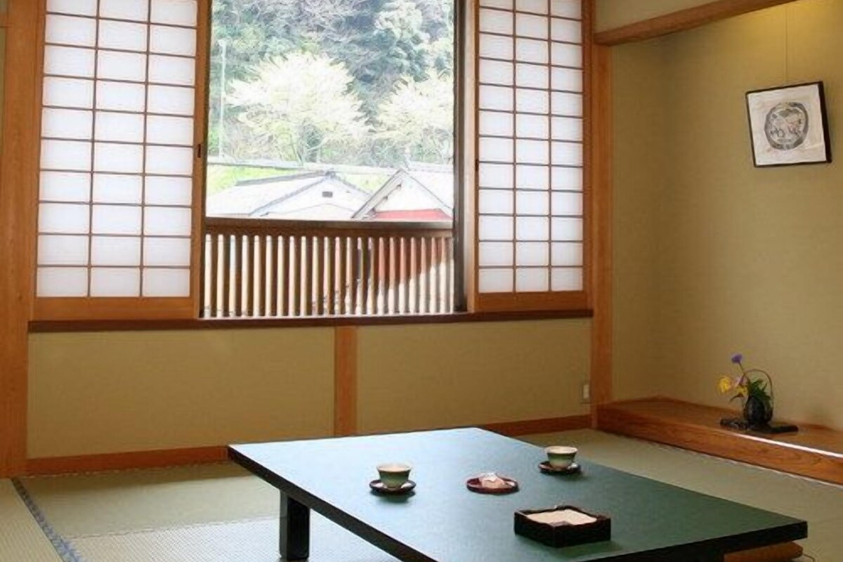 A traditional Japanese room with tatami flooring, a low table with tea utensils, and shoji screens.
