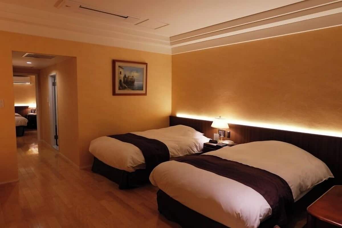 Une chambre d’hôtel avec deux lits, une table de chevet, une lampe et un tableau au mur.