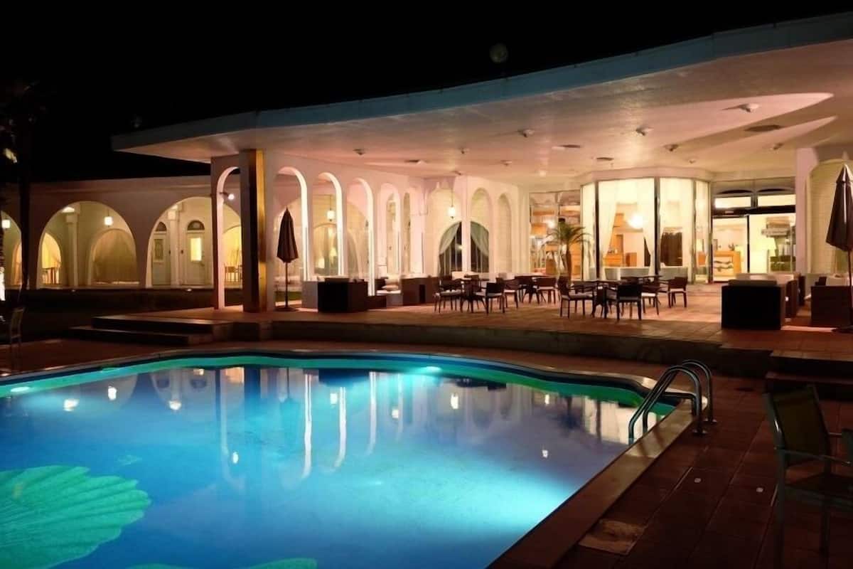 Un espace aménagé au bord de la piscine, comprenant une piscine, des sièges et un patio couvert.