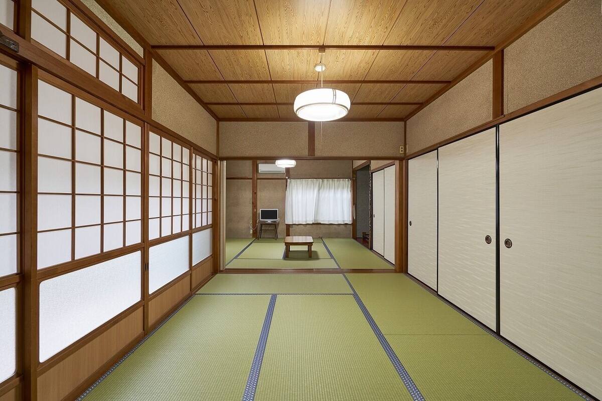 Una habitación japonesa tradicional con suelo de tatami, puertas correderas y un televisor.