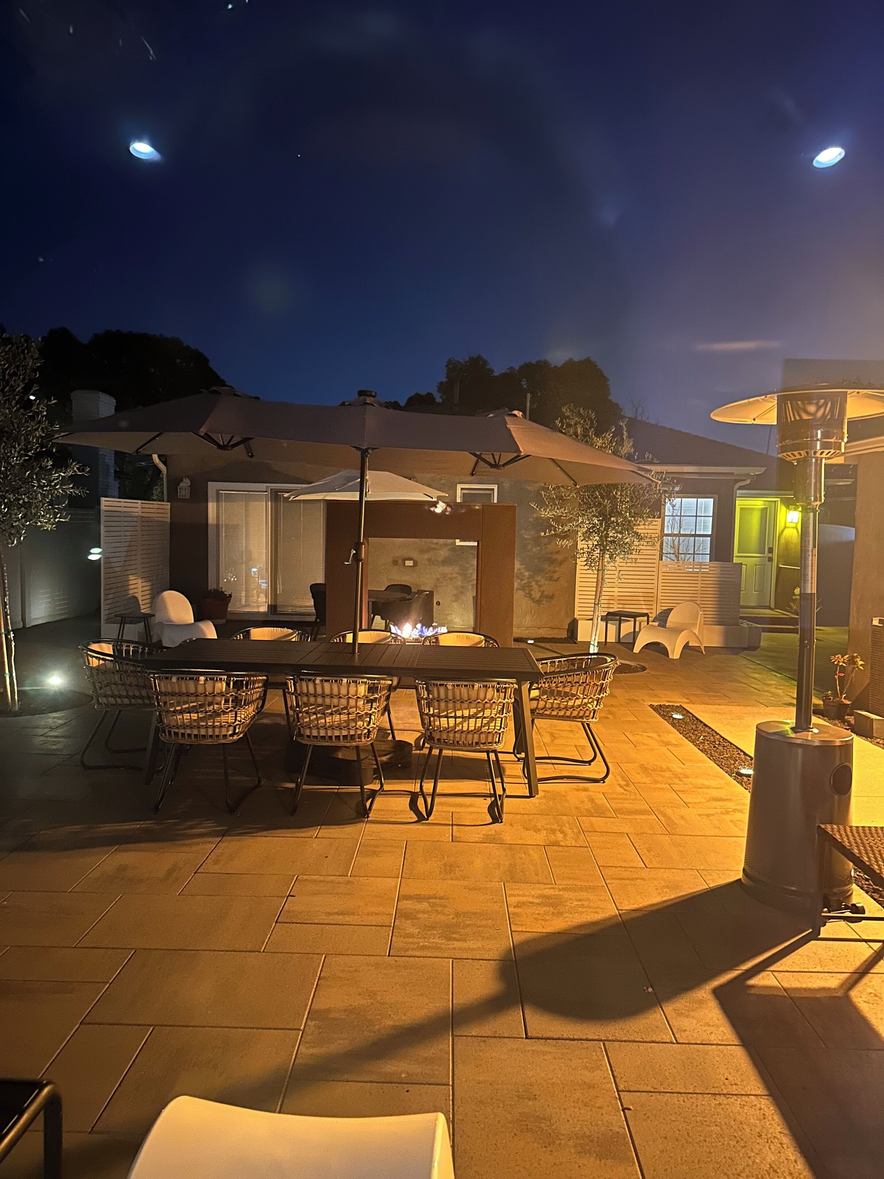 An outdoor patio with a fire pit, dining table, and chairs.