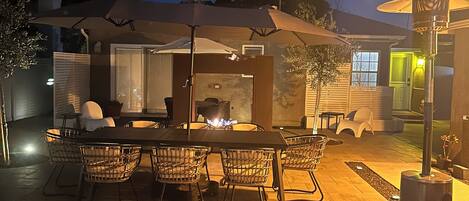 An outdoor patio with a fire pit, dining table, and chairs.