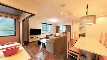 A modern living room with a TV, sofa, and dining area.