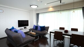 Una sala de estar moderna con televisor de pantalla plana, sofá, mesa de centro y mesa de comedor con sillas.