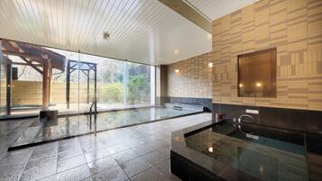 A modern indoor pool area with a glass enclosure, a wooden ceiling, and a tiled floor.