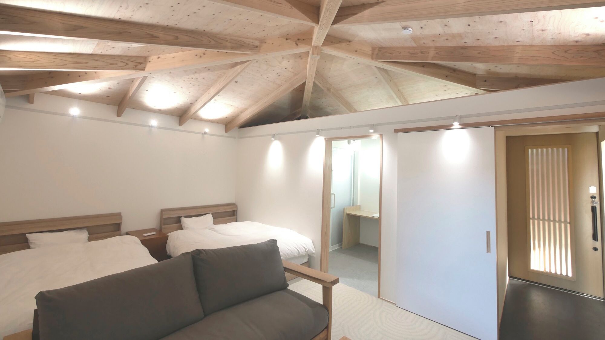 Una camera da letto con soffitto a falde, un letto, un divano e una porta scorrevole.