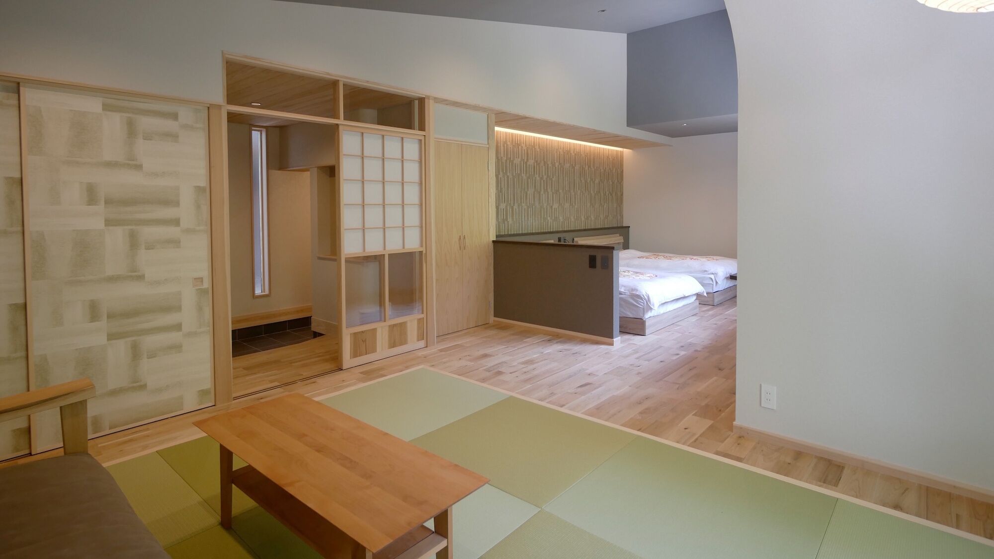 Una stanza con una porta scorrevole, angolo cottura, un letto e un tavolo di legno.
