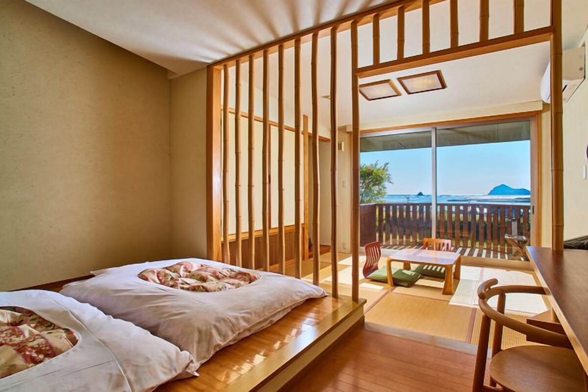 Una habitación con cama, una mesa y vista al océano.