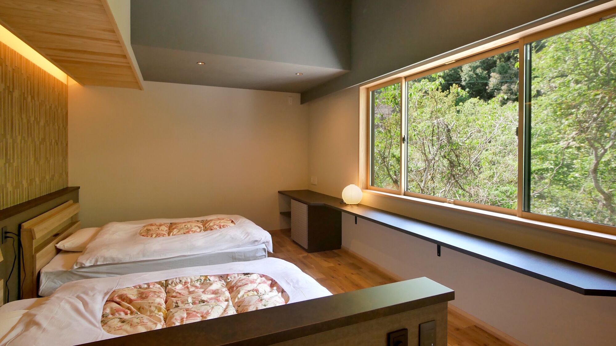 Camera da letto con due letti, un comodino, una finestra vista alberi e una luce a soffitto.