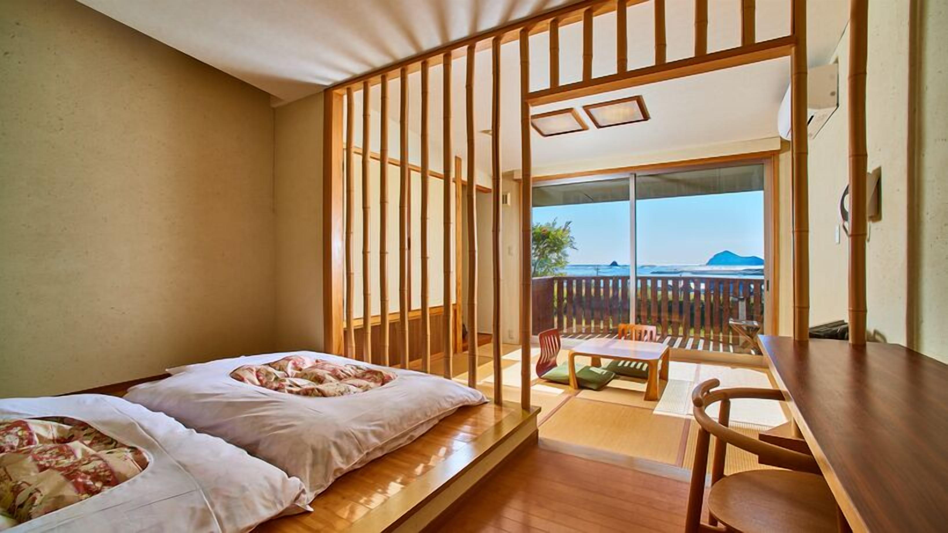 Una stanza con un letto, un tavolo e vista sull'oceano.