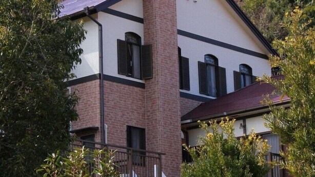 A two-story house with a brick chimney, white walls, and black trim. - Kids Pension Fruit Juice Awajishima (Awaji)