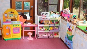 A playroom with a toy kitchen, a play table, and shelves with toys. - Kids Pension Fruit Juice Awajishima (Awaji)