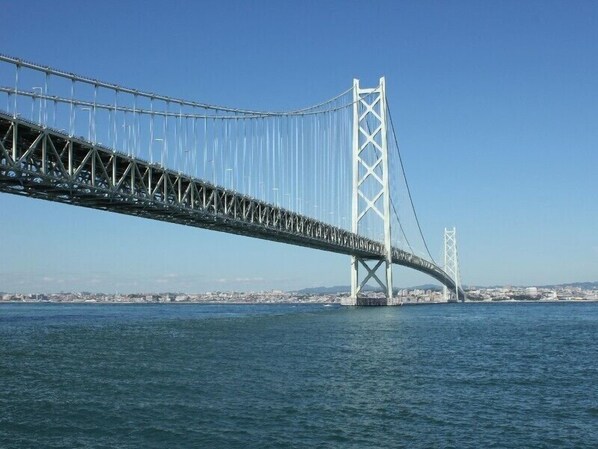 A large suspension bridge spanning a body of water with a cityscape in the background.