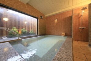 Un espace bien-être comprenant un jacuzzi, une douche et une vue sur la verdure environnante.