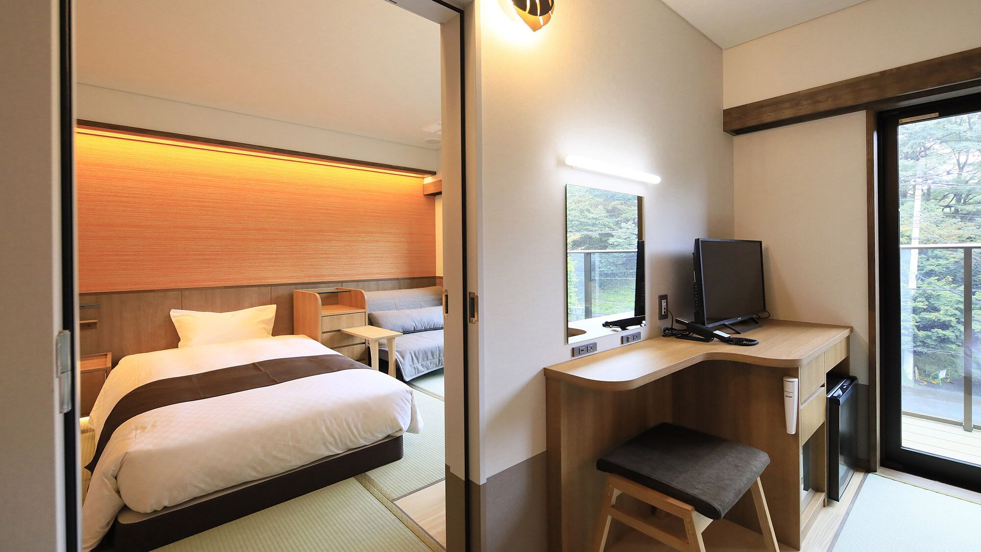 A hotel room with a bed, desk, chair, TV, and a window with a view.