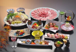Une variété de plats et de boissons sont disposés sur une table, notamment des sushis, des sashimis et un verre à martini.