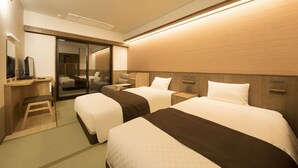 Ein Hotelzimmer mit zwei Betten, einem Schreibtisch, einem Stuhl, einem Spiegel und einer Schiebetür zum Badezimmer.