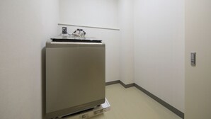 Ein kleiner, leerer Raum mit einer Küchenzeile, die einen Kühlschrank, eine Mikrowelle und eine kleine Arbeitsplatte beinhaltet.