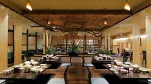 Ein Restaurant mit langen Holztischen, Stühlen und hängenden Leuchten.