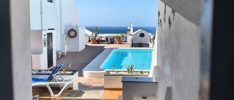 A pool area with a view of the sea, a lifebuoy, and exercise mats.
