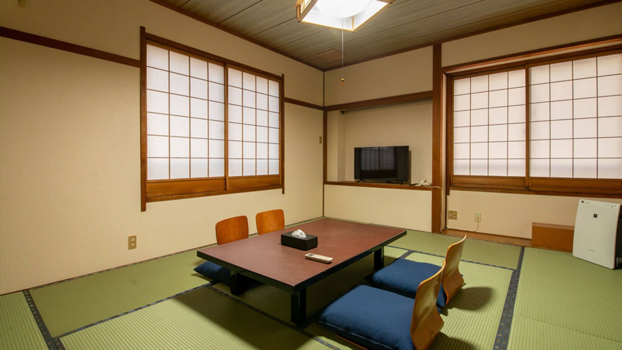 A traditional Japanese room with tatami flooring, a low table, and sliding doors.