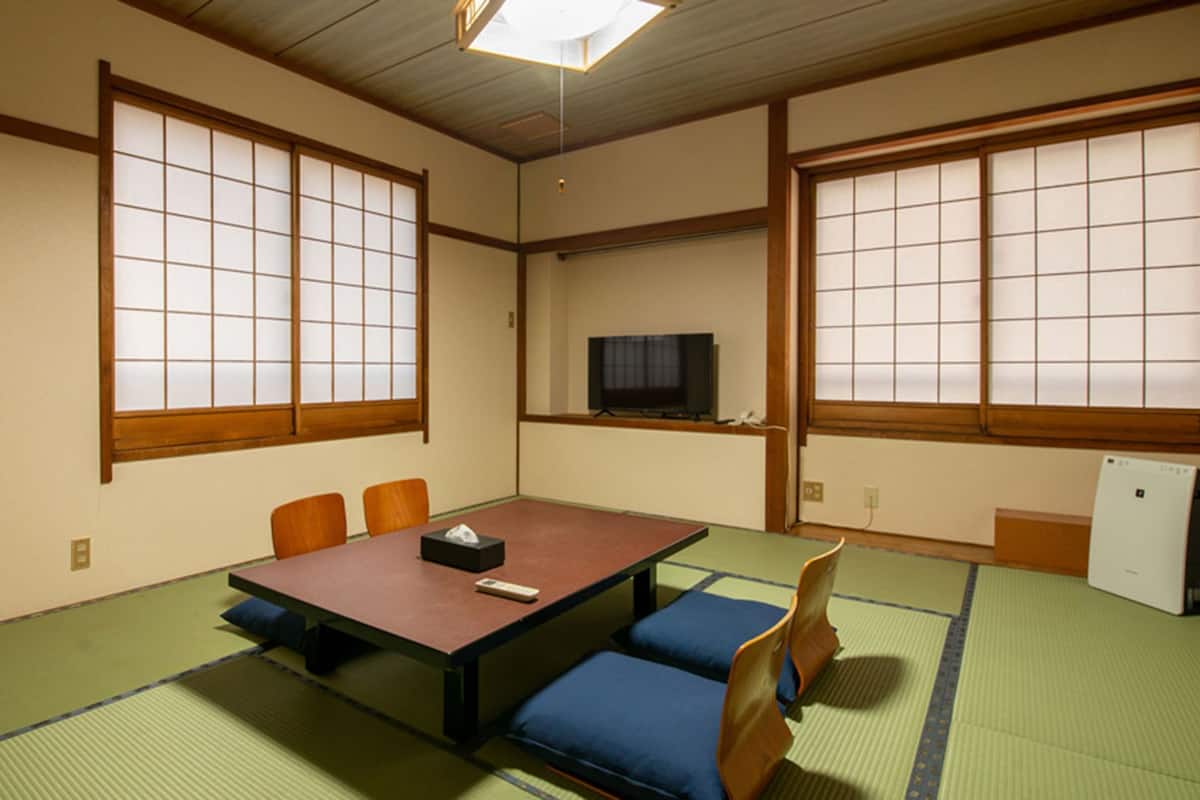 A traditional Japanese room with tatami flooring, a low table, and sliding doors.