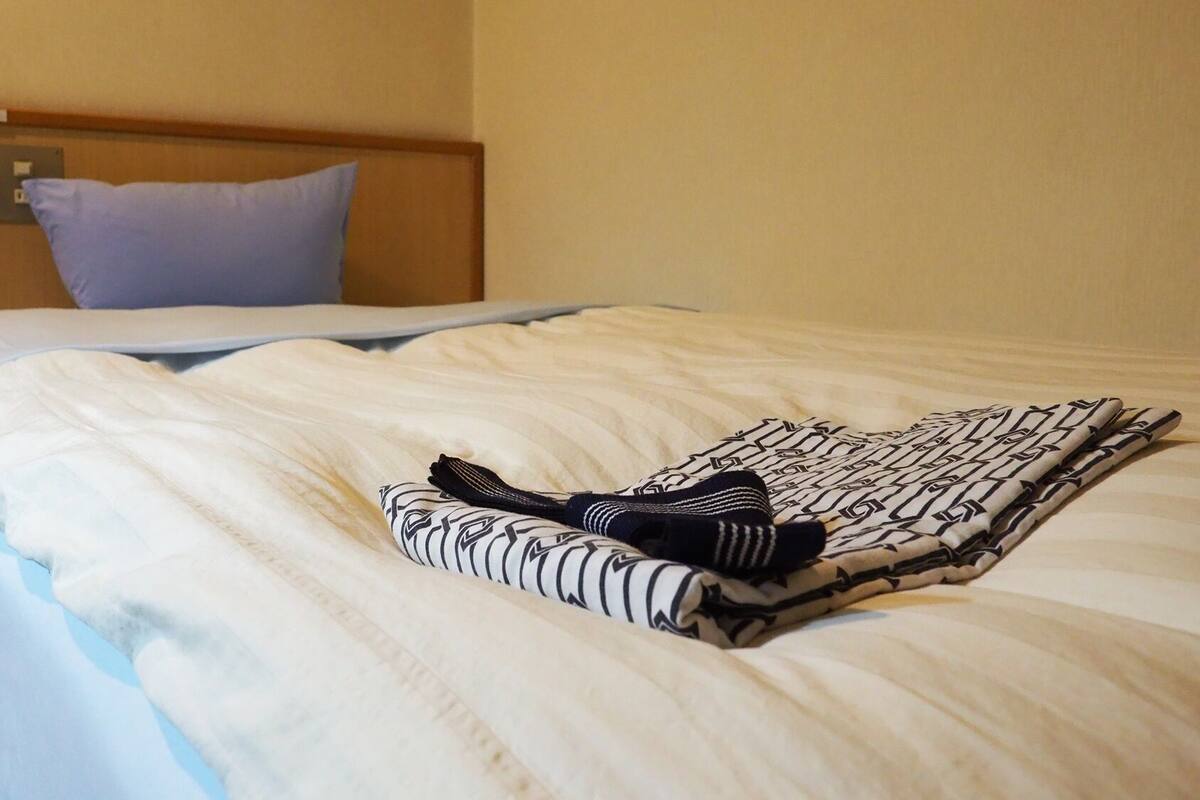 A neatly made bed with a folded blanket and a pair of socks on the bed.