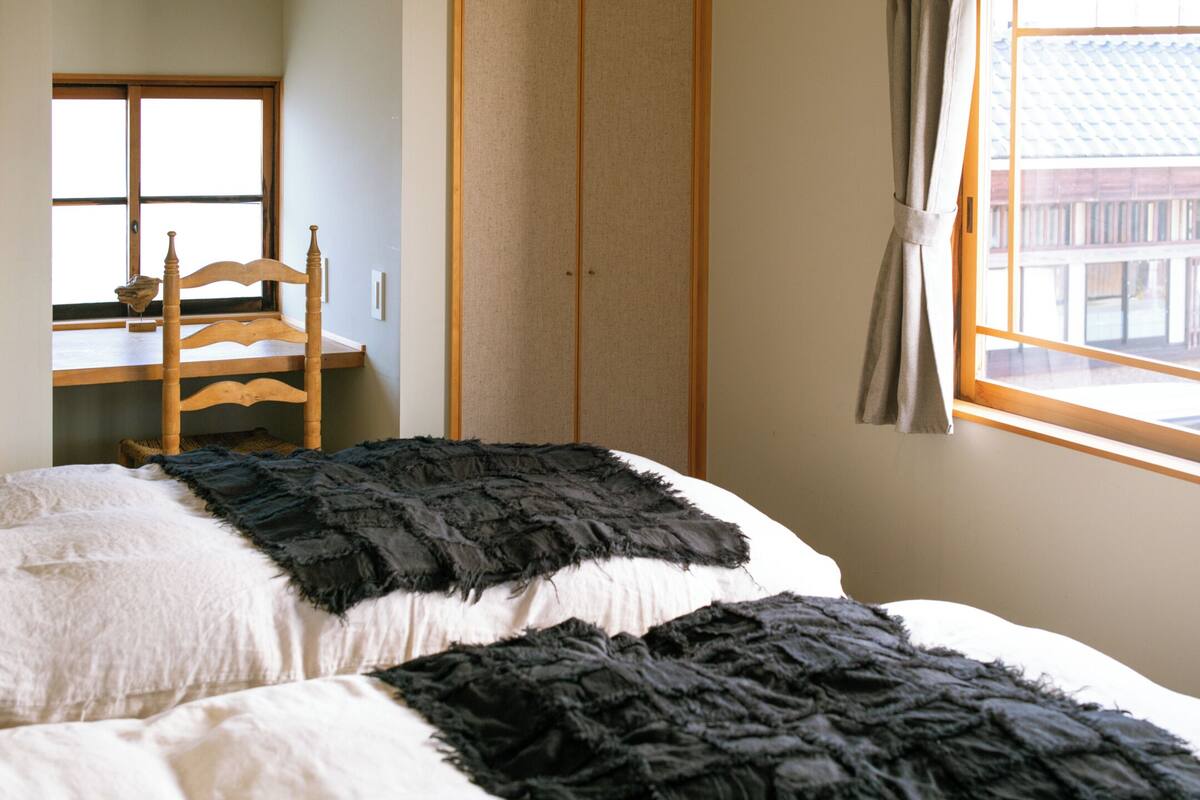A bedroom with a bed, a wooden chair, a window, and a sliding door.