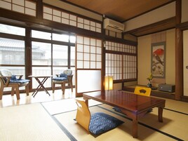 A traditional Japanese room with tatami flooring, a low table, and chairs.