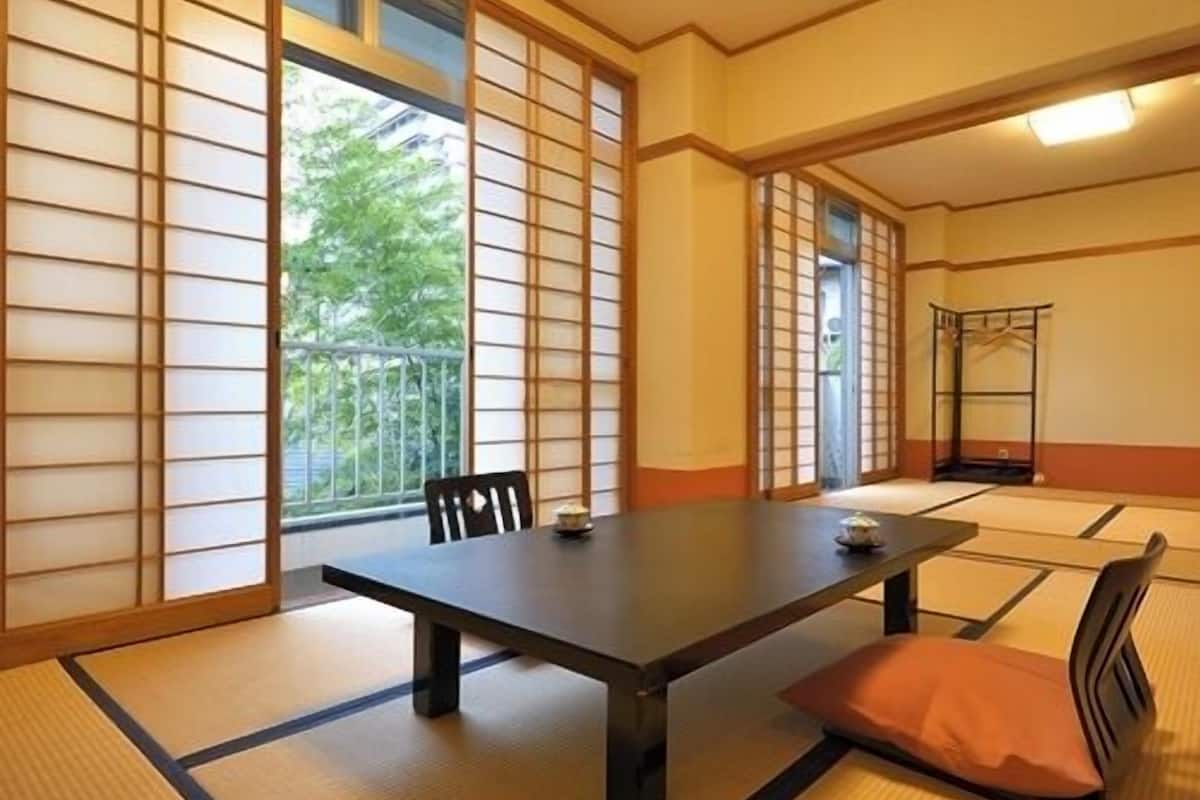 Una habitación tradicional japonesa con suelo de tatami, una mesa baja y puertas correderas.