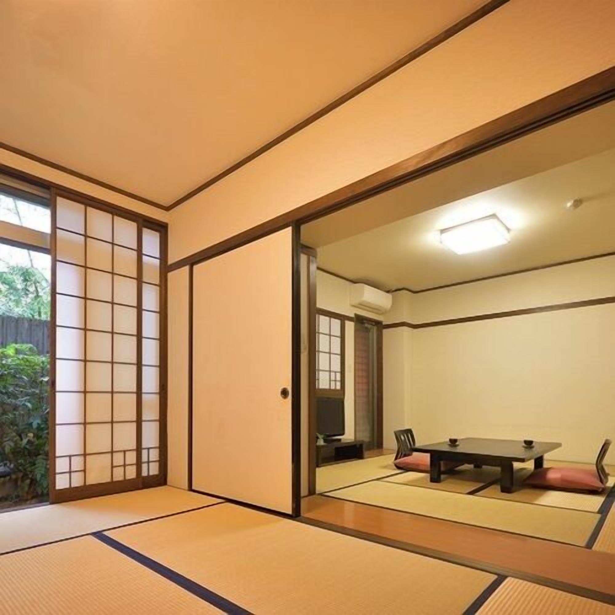 A tatami mat room with a sliding door, a table, and chairs.