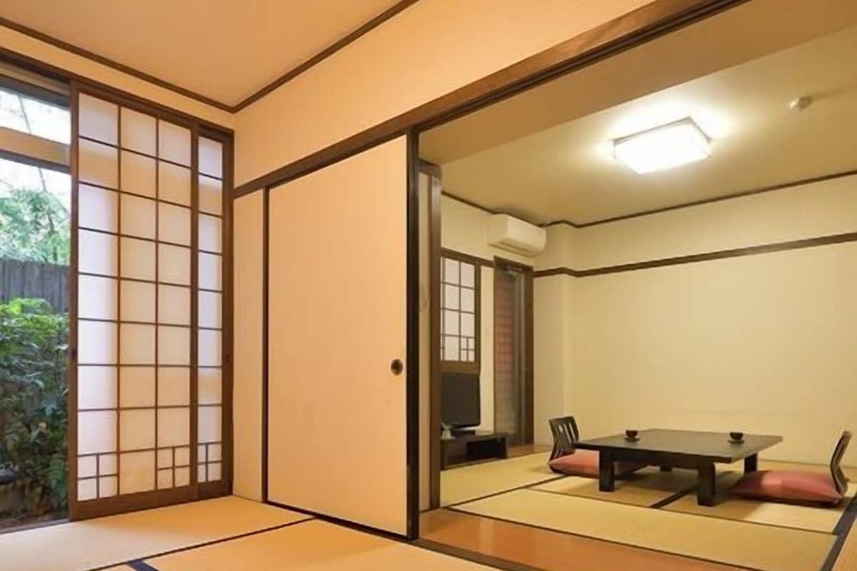 Una habitación con esteras de tatami, una puerta corredera, una mesa y sillas.
