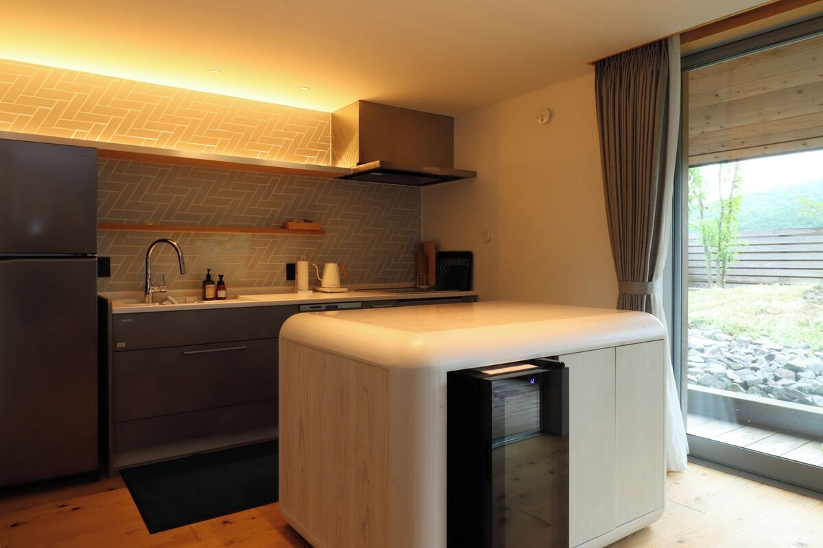 A compact kitchen with a refrigerator, sink, and a built-in oven.