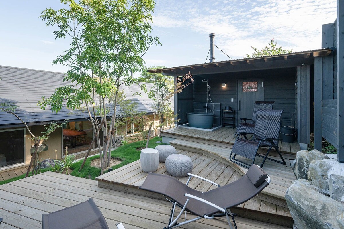 A wooden deck with lounge chairs and a hot tub.