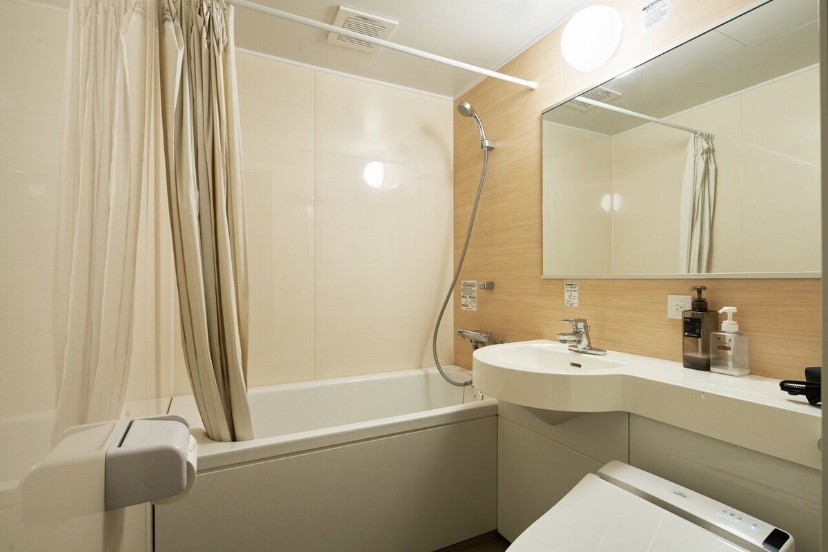 A modern bathroom with a bathtub, a sink, a mirror, and a showerhead.