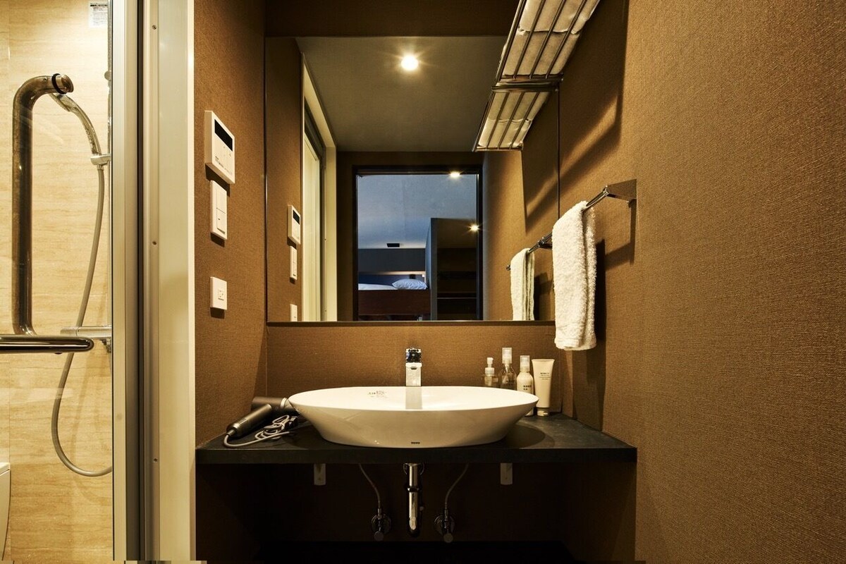 A bathroom with a large sink, a mirror, a towel rack, and a shower.