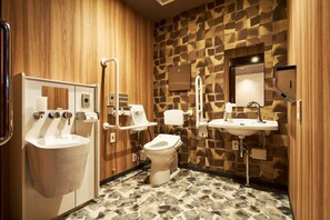 A modern bathroom with a wooden wall, a toilet, a sink, and a hand dryer. - B/C Hotel Naha Rent-a-car Hotel (Minokamo)