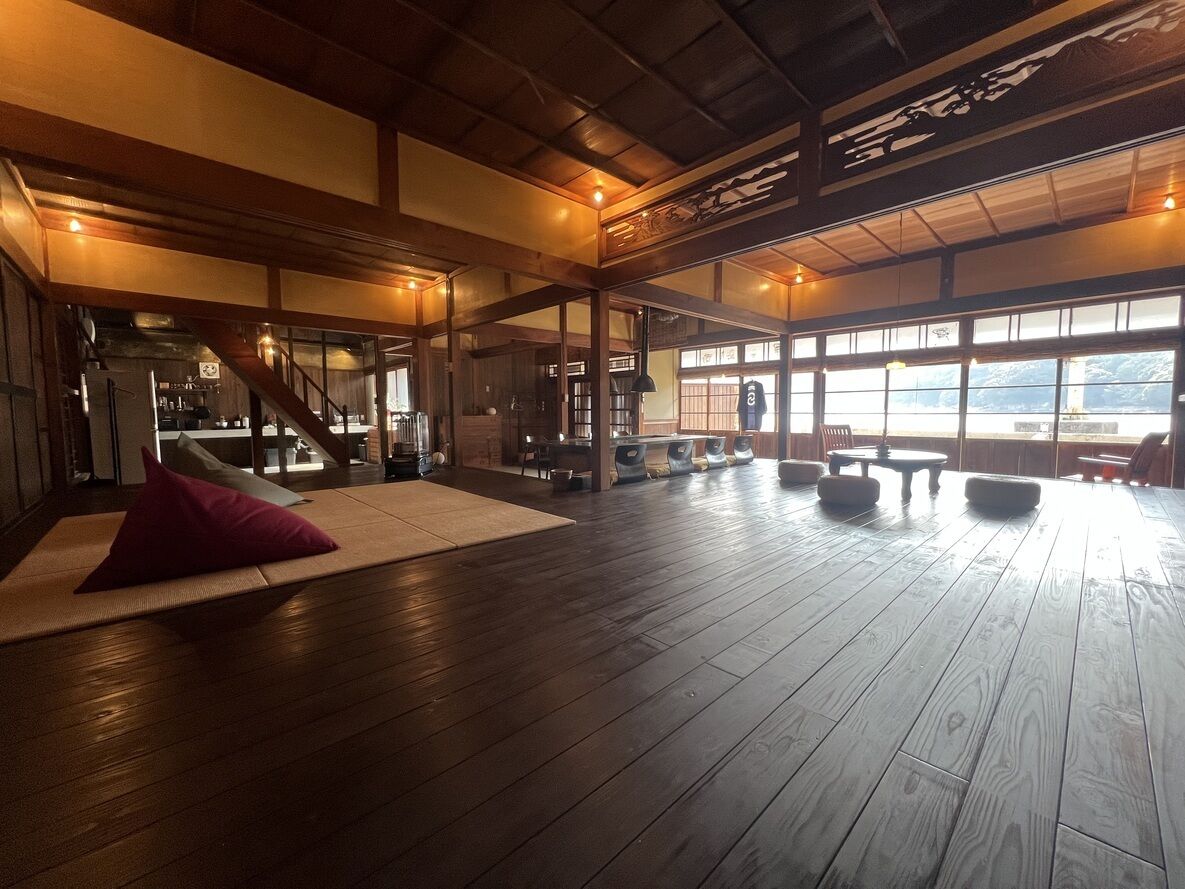 Een ruime kamer met een houten vloer, een tatami mat en een groot raam met uitzicht.