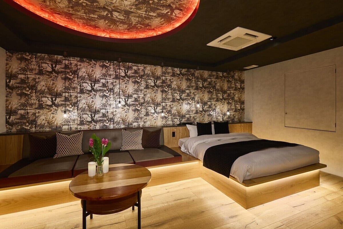Un dormitorio moderno con cama, zona de estar y una mesa con flores.