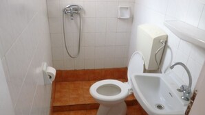 A small bathroom with a toilet, sink, and shower. - Vasilis Ios Place Room 1 (Chora)