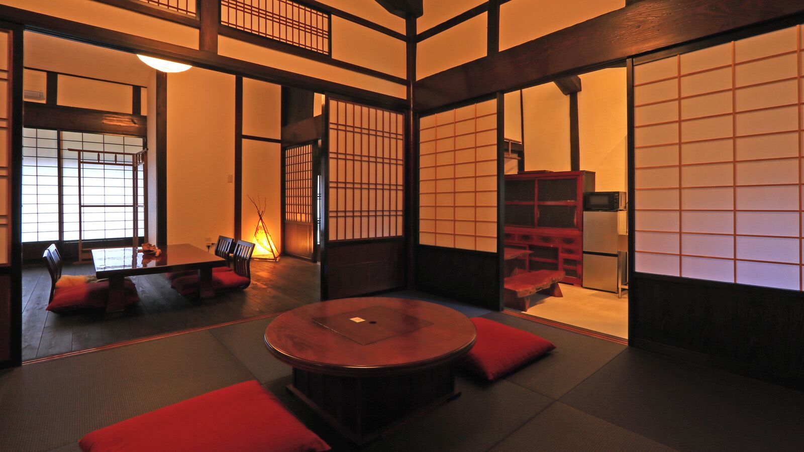 Una habitación japonesa tradicional con suelo de tatami, una mesa redonda y muebles de madera bajos.