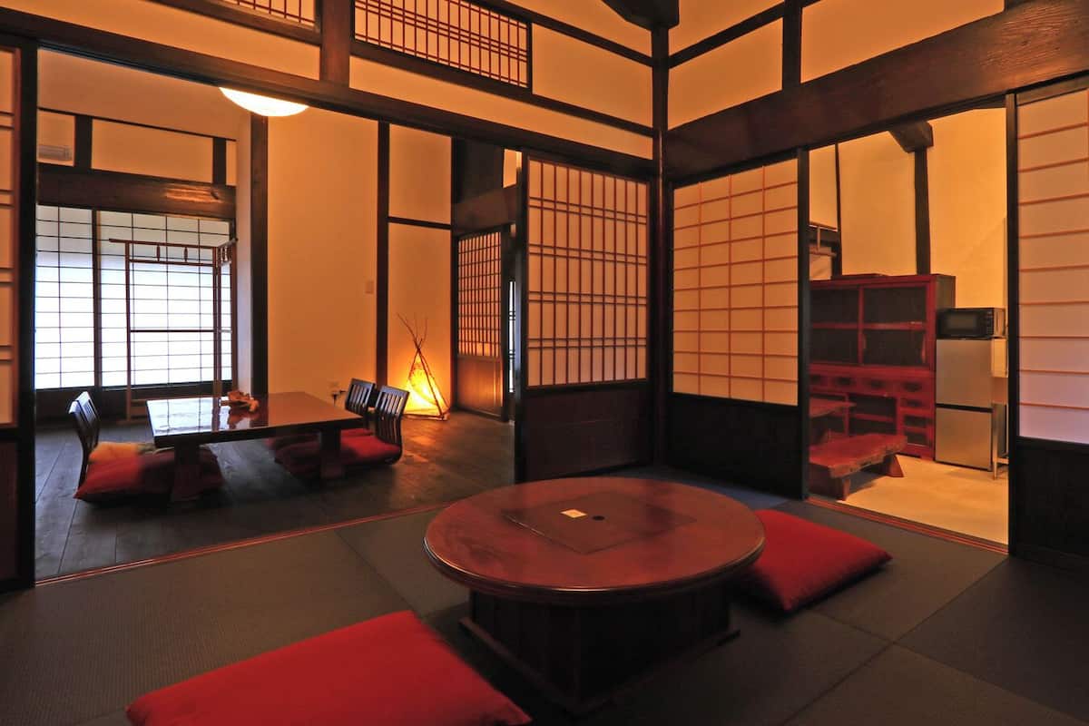 A traditional Japanese room with tatami flooring, a round table, and low wooden furniture.
