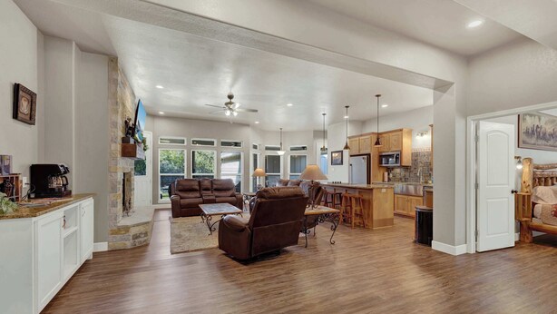 A spacious living area with a fireplace, a seating area with a recliner, and a kitchen with wooden cabinets. - Crazy Horse-Close to Canyon Lake Marina! (Canyon Lake)
