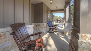 A covered porch with wooden rocking chairs and stone walls. - Crazy Horse-Close to Canyon Lake Marina! (Canyon Lake)