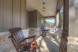 A covered porch with wooden rocking chairs and stone walls.